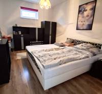 Schlafzimmer in einem Einfamilienhaus mit Holzboden, Bett und schwarzen Möbeln.