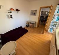 Ein Zimmer mit Bett und Ablageregalen, Boden mit Holzdekor in einer 3-Zimmer-Wohnung.
