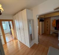 Der Flur in der 3-Zimmer-Wohnung mit einem Boden in Holzoptik, weißen Schränken und einem Spiegel.