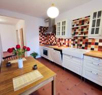 Küche in einer 4-Zimmer-Wohnung mit bunten Fliesen und Holzmuster auf dem Tisch.