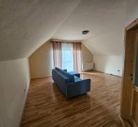 Ein Interieur mit einem Boden in Holzoptik, einem Sofa und Vorhängen in einem Gebäude.