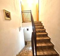 Treppenhaus im Gebäude mit Fliesenverkleidung und Geländer, beleuchtet von weißem Licht.