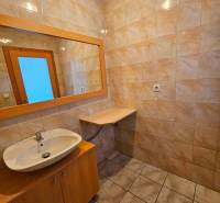 Badezimmer mit Keramikfliesen, Waschbecken und Spiegel im Gebäude.