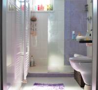 Badezimmer in einer Einzimmerwohnung mit Toilette, Waschbecken und Fenster. Helle Fliesen sind dominant.