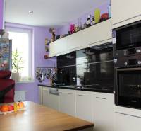 Küche in einer Einzimmerwohnung mit einem hellen Schrank, einem Stuhl und Obst auf dem Tisch.