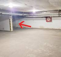 Unterirdischer Parkplatz in der Garage mit einem Stellplatz an der Wand und Autos.