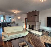 Ein geräumiges Wohnzimmer mit Kamin in einem Einfamilienhaus, helle Möbel, Boden mit Holzdekor.