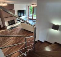 Wohnzimmer mit Kamin und Treppe in einem Einfamilienhaus, Bodenbelag mit Holzdekor.