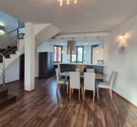 Innenraum eines Einfamilienhauses mit Küche, Esszimmer und Treppe auf einem Boden mit Holzdekor.