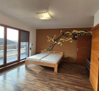 Ein Zimmer in einem Einfamilienhaus mit einem Boden in Holzoptik, einem Doppelbett und einer Terrasse.