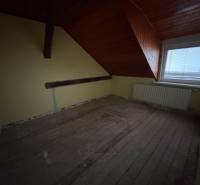 Dachgeschosszimmer in einem Einfamilienhaus mit Balken und Dachfenster.