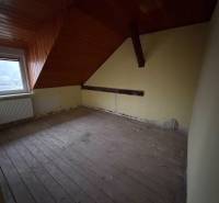 Ein Dachzimmer mit einer Holzdecke und einem Boden mit Holzdekor in einem Einfamilienhaus.