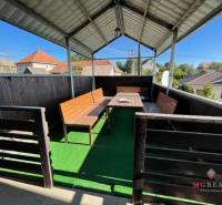 Überdachte Terrasse eines Einfamilienhauses in der Hauptstraße in Podhradie mit Holzmöbeln und Kunstrasen.