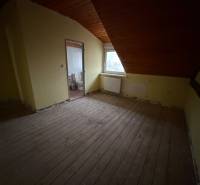 Ein Zimmer im Dachgeschoss eines Einfamilienhauses mit Holzbalkendecke und Blick auf die Stadt.