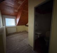 Dachgeschosszimmer mit Holzdecke und angrenzendem Badezimmer in einem Einfamilienhaus.