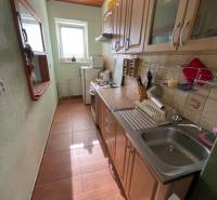 Eine schmale Küche in einem Einfamilienhaus mit Fenster und Geräten, dominiert von einem Holzdekor der Schränke.