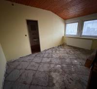 Ein Zimmer in einem Einfamilienhaus mit unfertigem Boden und einer Holzdecke.