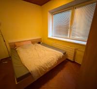 Schlafzimmer im Einfamilienhaus mit Ehebett, Lampe und großem Fenster mit Jalousien.