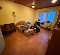 Schlafzimmer in einem Einfamilienhaus mit Bett, Tisch, Stuhl und Boden in Holzoptik.