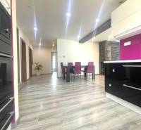 Eine Küche in einem Einfamilienhaus mit einem Boden in Holzoptik und violetten Stühlen.