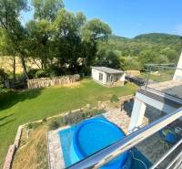 Der Garten des Einfamilienhauses in Melčice-Lieskové mit einem Pool, Bäumen und Brennholz.