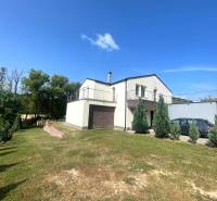 Ein Einfamilienhaus in Melčice-Lieskové mit einem weitläufigen Garten und einer Terrasse, mit einem Auto auf der Zufahrt.