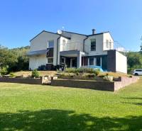 Ein Einfamilienhaus in Melčice-Lieskové mit gepflegtem Garten und Parkmöglichkeiten auf einem Rasenstück.