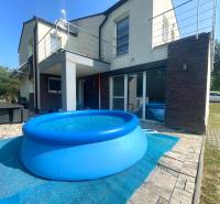 Ein Einfamilienhaus in Melčice-Lieskové mit Pool und Terrasse mit Rattanmöbeln.