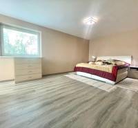 Schlafzimmer in einem Einfamilienhaus mit Bett, Kommode und Boden mit Holzdekor.