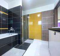 Ein Badezimmer in einem Einfamilienhaus mit Badewanne, Dusche und bunten Fliesen.