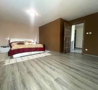 Ein Schlafzimmer im Einfamilienhaus mit Bett, Schrank und Boden mit Holzdekor.