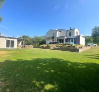 Ein Einfamilienhaus in Melčice-Lieskové, großer Garten, Garage, blauer Himmel, Sommertag.