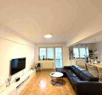 Wohnzimmer in einer 4-Zimmer-Wohnung mit Holzboden und schwarzem Sofa.