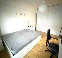 Schlafzimmer mit Einbauschränken, Holzboden und einfacher Möblierung in einer Vierzimmerwohnung.