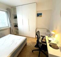 Schlafzimmer in einer 4-Zimmer-Wohnung mit weißen Möbeln und einem Boden in Holzoptik.