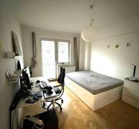 Schlafzimmer in einer 4-Zimmer-Wohnung mit Schreibtisch und Bett, Boden mit Holzdekor.