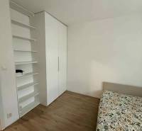 Schlafzimmer mit Schrank, Regalen und Bett in einer Vierzimmerwohnung. Boden mit Holzdekor.