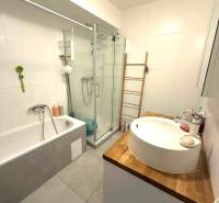 Badezimmer mit Badewanne, Dusche und Waschbecken auf einer Holzplatte in einer 4-Zimmer-Wohnung.