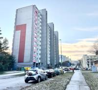 Ein Wohnblock in der Drobného-Straße in Bratislava - Dúbravka, umgeben von Autos und Grünflächen.