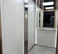 Der Innenraum des Aufzugs mit einer Edelstahlplatte und einem Spiegel in einer Einzimmerwohnung.