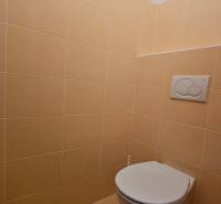 Toilette mit beigefarbenen Fliesen in Geschäftsräumen.