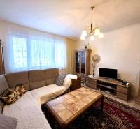 Wohnzimmer einer 3-Zimmer-Wohnung mit Sofa, Kronleuchter, Holzboden und Schränken.