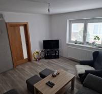 Wohnzimmer in einem Einfamilienhaus mit Holzboden, Fernseher und Sitzgelegenheiten.