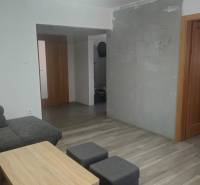 Wohnzimmer in einem Einfamilienhaus, graues Sofa, hölzerner Couchtisch, Boden mit Holzdekor.