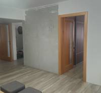 Innenraum eines Einfamilienhauses mit Holzboden, Fernseher und offenen Türen.