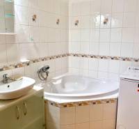 Badezimmer mit Fliesen, Badewanne und Waschmaschine in einer 2-Zimmer-Wohnung.