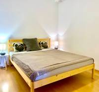 Schlafzimmer in einer 2-Zimmer-Wohnung mit Holzelementen und Kissen auf dem Bett.