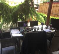 Einfamilienhaus mit Sitzbereich auf der Terrasse, einschließlich Bodenbelag in Holzoptik und Gartenbegrünung.