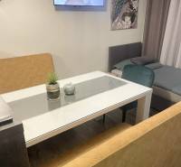 Wohnbereich mit Fernseher in einem Einfamilienhaus, Glastisch, Sofas, Pfauenbild, Boden mit Holzdekor.