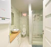 Badezimmer im Einfamilienhaus mit Waschbecken, Duschkabine und Toilette, helle Fliesen.